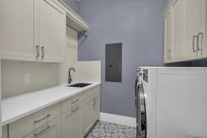 Laundry room with cabinet space, electric panel, washing machine and clothes dryer, and light tile patterned floors
