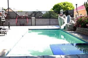 Integrated pool / spa featuring a water slide, a fenced backyard, and a patio