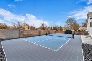 View of tennis court with a patio area