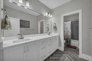 Full bath with double vanity, shower / bathtub combination with curtain, and parquet flooring