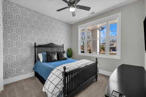 Carpeted bedroom featuring wallpapered walls and a ceiling fan