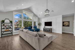 Living room with a high ceiling, light wood-style floors, ceiling fan, and hanging lights