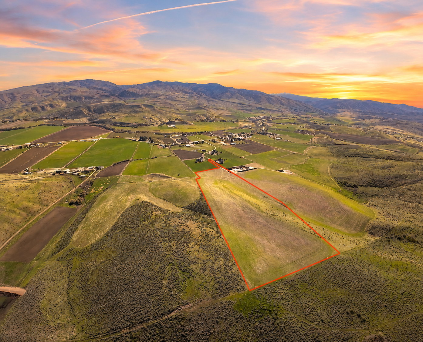 Expansive land parcel outlined in red, featuring varied terrain including open fields and sloped, brush-covered areas