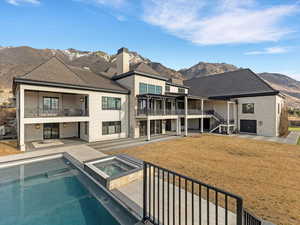 Back of house with a patio area, a mountain view, a balcony, a pool with connected hot tub, and stone siding