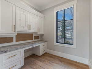 Unfurnished office with built in study area and light wood-style floors