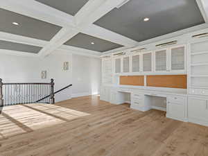 Homework room featuring built in desk, light wood-type flooring, recessed lighting, coffered ceiling, and built in shelves