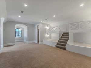 Bedroom featuring carpet, arched walkways, and suspended lighting