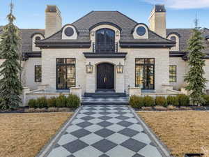 French country home featuring a high end roof, a front yard, and a chimney