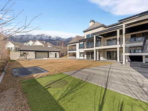 View of grassy yard with a balcony, a patio area, and a mountain view
