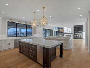 Kitchen featuring dual tone cabinets, light stone countertops, tasteful backsplash, pendant lighting, and open floor plan