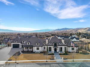 French country inspired facade featuring concrete driveway, a chimney, stone siding, and a mountain view