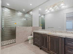 Bathroom with a shower stall, vanity, tile walls, and recessed lighting
