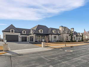 French provincial home with decorative driveway and a garage