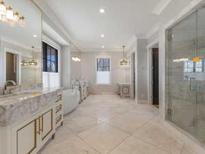 Full bathroom with a shower stall, two vanities, a soaking tub, recessed lighting, and ornamental molding
