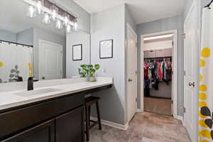 Primary bathroom featuring modern fixtures, updated lighting, and walk-in closet access.