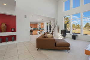 Living area featuring light tile patterned floors, a high ceiling, and recessed lighting