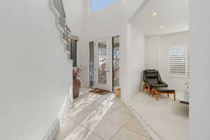 Foyer with light tile patterned floors, a high ceiling, french doors, and recessed lighting