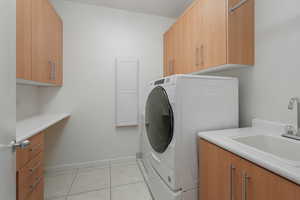 Laundry area with cabinet space and light tile patterned flooring