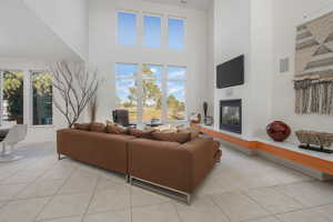 Living room with a high ceiling, a glass covered fireplace, and light tile patterned floors