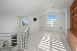 Spare room featuring light carpet, plenty of natural light, recessed lighting, and lofted ceiling