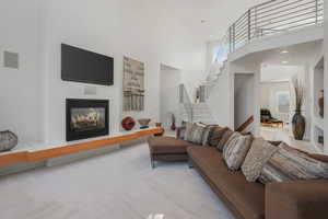 Living area featuring a glass covered fireplace, a high ceiling, and carpet flooring