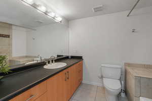 Bathroom with vanity, a textured ceiling, and light tile patterned flooring