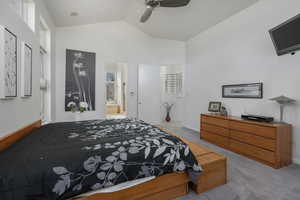 Bedroom featuring light carpet, lofted ceiling, ceiling fan, and ensuite bathroom