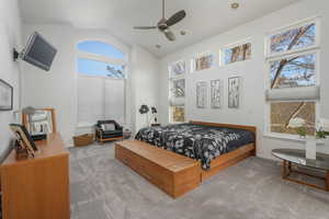 Bedroom with a high ceiling, ceiling fan, and carpet flooring