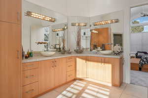 Bathroom featuring double vanity, ensuite bath, and light tile patterned floors