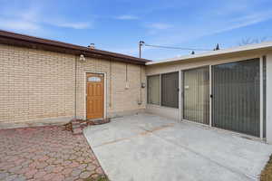 View of exterior entry with a patio and brick siding