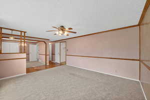 Empty room with light carpet, a ceiling fan, and a textured ceiling