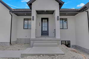 Entrance to property with stucco siding and a porch