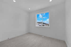 Empty room with light carpet and recessed lighting