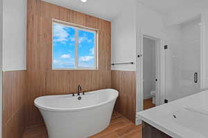 Bathroom featuring a shower stall, a freestanding tub, vanity, and wood tiled floors