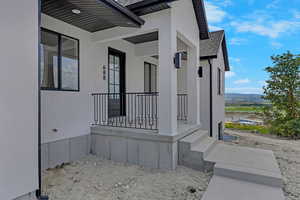 Entrance to property featuring covered porch, stucco siding, a shingled roof, and a mountain view