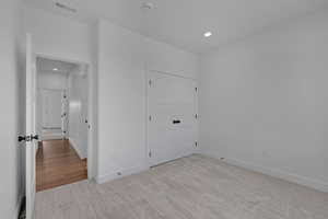 Unfurnished bedroom featuring light colored carpet, recessed lighting, and a closet