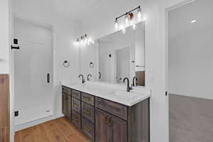 Full bath with double vanity, a stall shower, and wood finish floors
