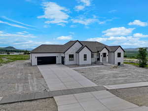 Modern inspired farmhouse with a mountain view, stucco siding, concrete driveway, an attached garage, and a shingled roof