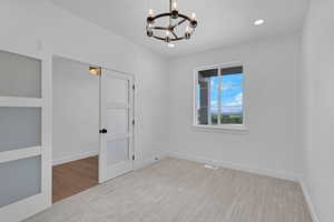 Unfurnished room featuring suspended lighting and baseboards