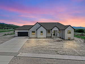 Modern inspired farmhouse with a shingled roof, concrete driveway, a mountain view, and stucco siding