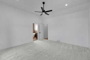 Unfurnished bedroom featuring light colored carpet, ceiling fan, ensuite bathroom, recessed lighting, and lofted ceiling