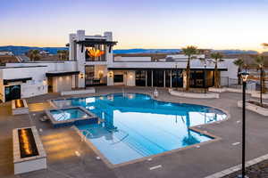 Pool at dusk featuring a pool with connected hot tub, a mountain view, and a patio