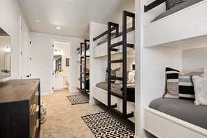 Bedroom with light colored carpet, recessed lighting, and connected bathroom