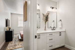 Full bathroom featuring double vanity and dark wood-type flooring