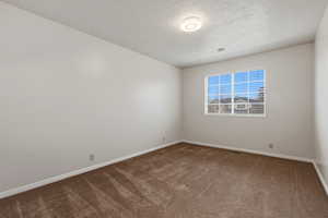 Carpeted spare room featuring baseboards and a textured ceiling