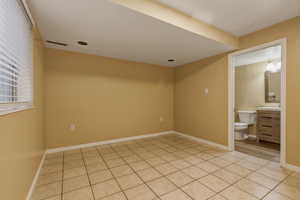 Unfurnished bedroom with light tile patterned floors and connected bathroom