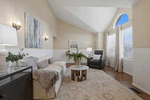 Sitting room with vaulted ceiling and wood finished floors