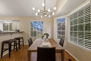 Dining area with dark wood-style flooring, a chandelier, and lofted ceiling