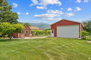 View of green lawn featuring an outbuilding, a mountain view, and a detached garage