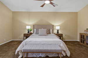 Bedroom with dark colored carpet and a ceiling fan